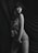 A monochrome image features a person posing with a cloth draped around their body. The background appears to be made of soft, flowing fabric, creating a sense of elegance and softness. The person exudes confidence, enhanced by the sophisticated drapery and lighting.