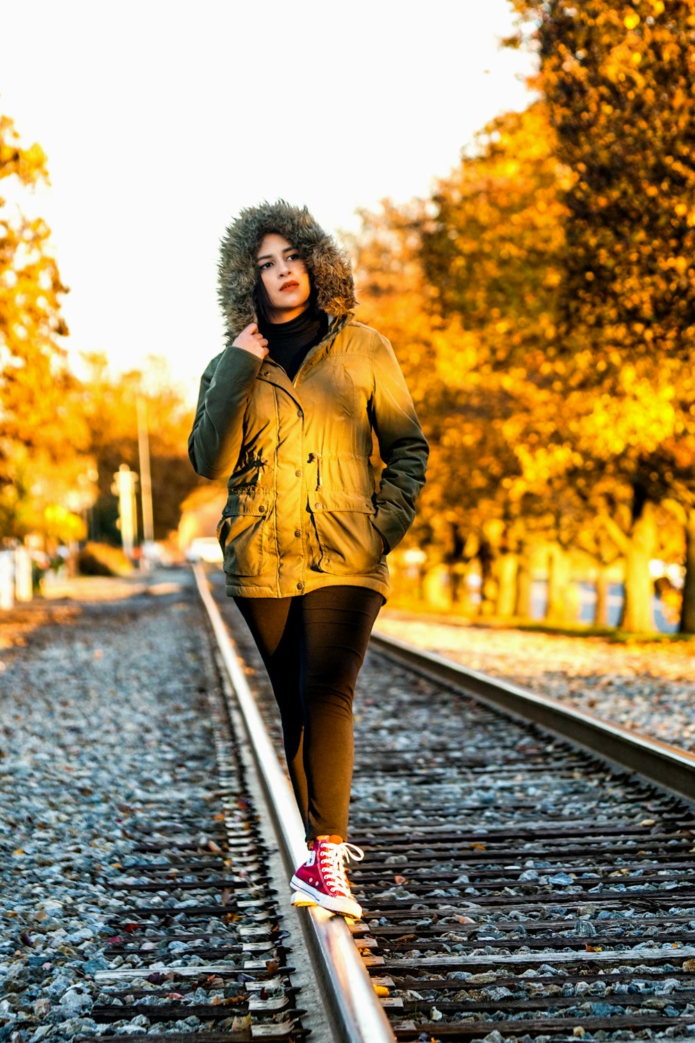 donna in cappotto marrone in piedi sul sentiero durante il giorno