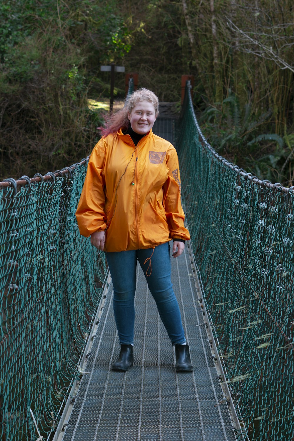 Mujer en chaqueta amarilla de pie en puente colgante