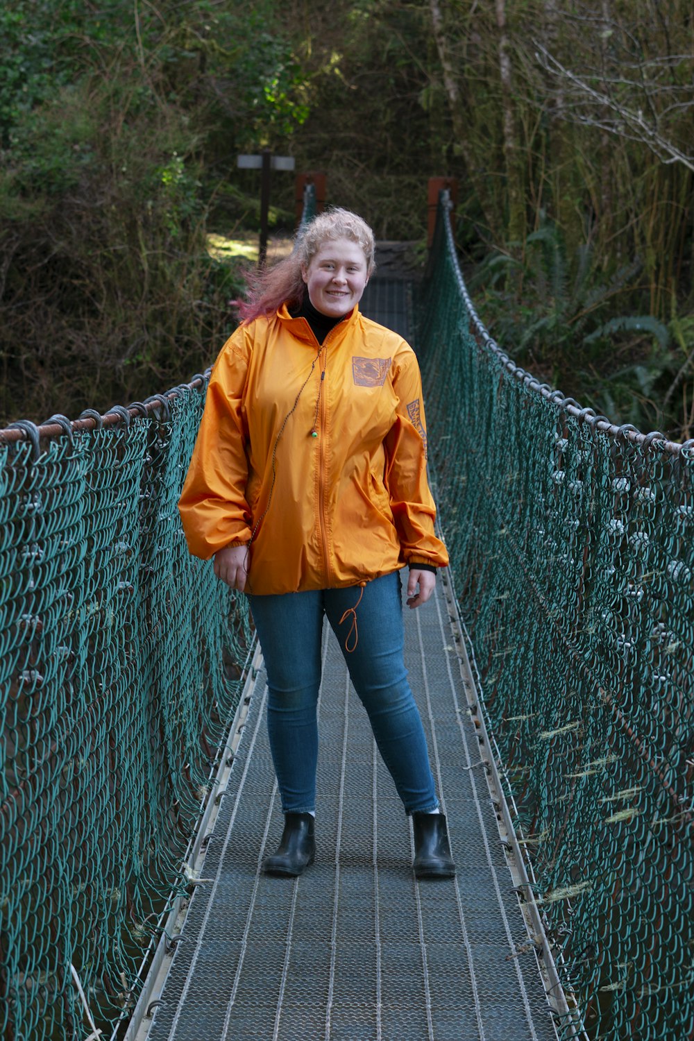 woman in yellow jacket standing on hanging bridge