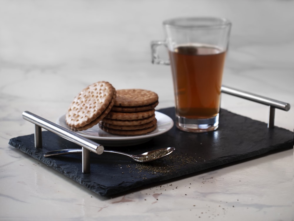 clear glass mug with brown liquid on black wooden table