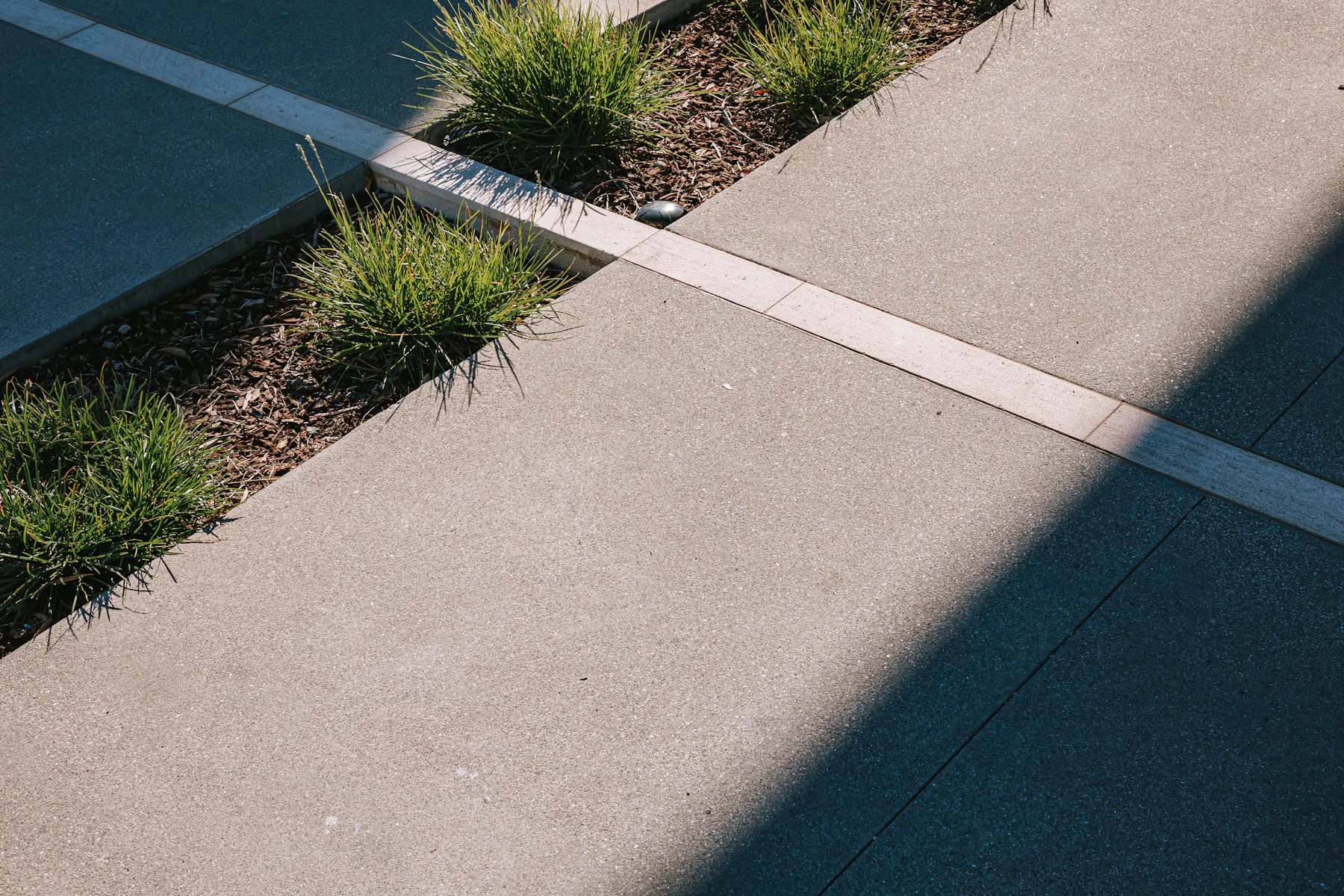Textured concrete sidewalk panels with clean joints beside landscaping mulch
