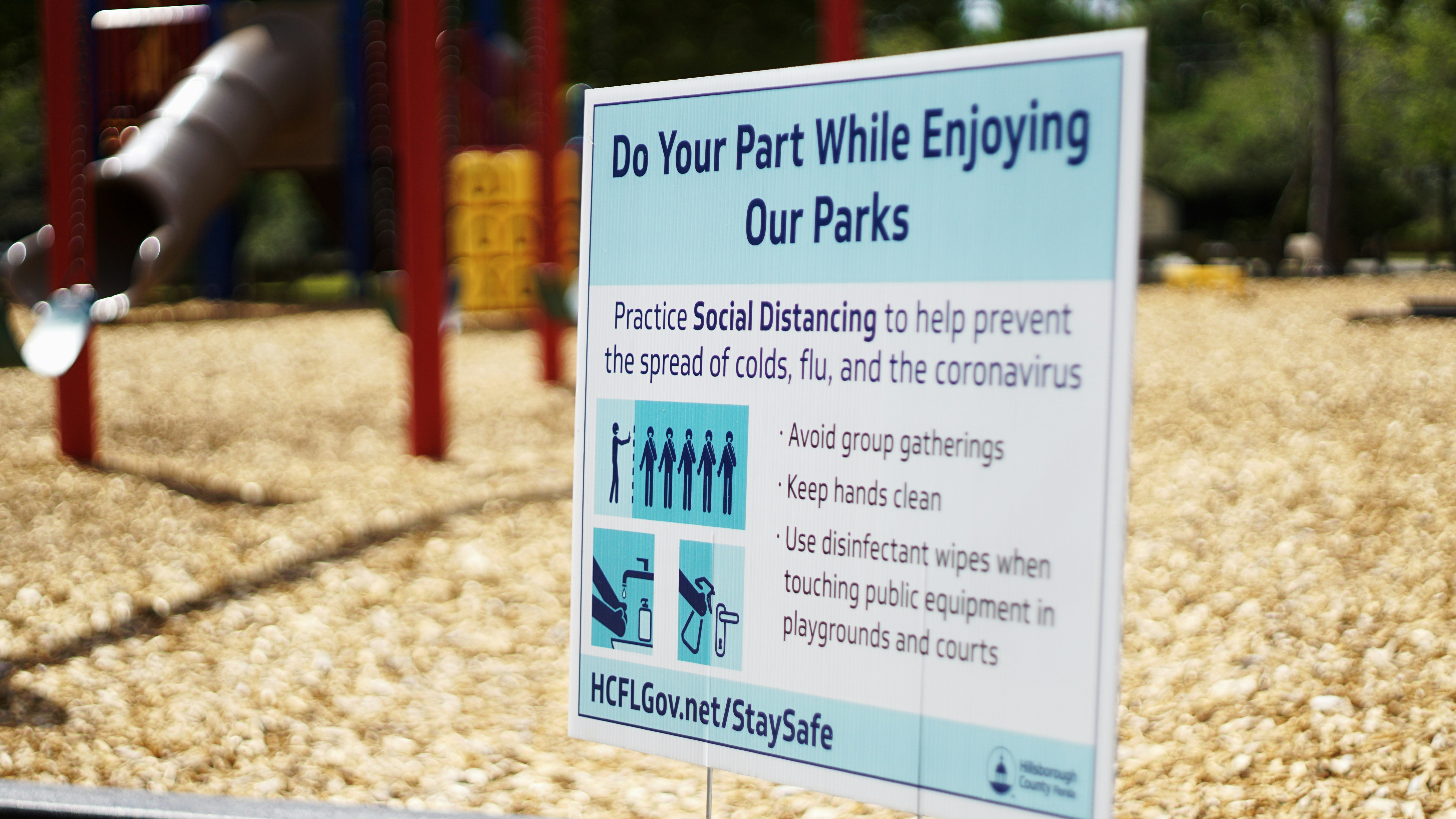 Social distancing sign with empty playground.