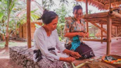 Community members working together in a sago processing workshop surrounded by tropical plants.