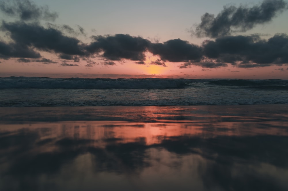 corpo de água sob o céu nublado durante o pôr do sol