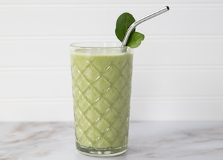 green and white drink with straw in clear drinking glass