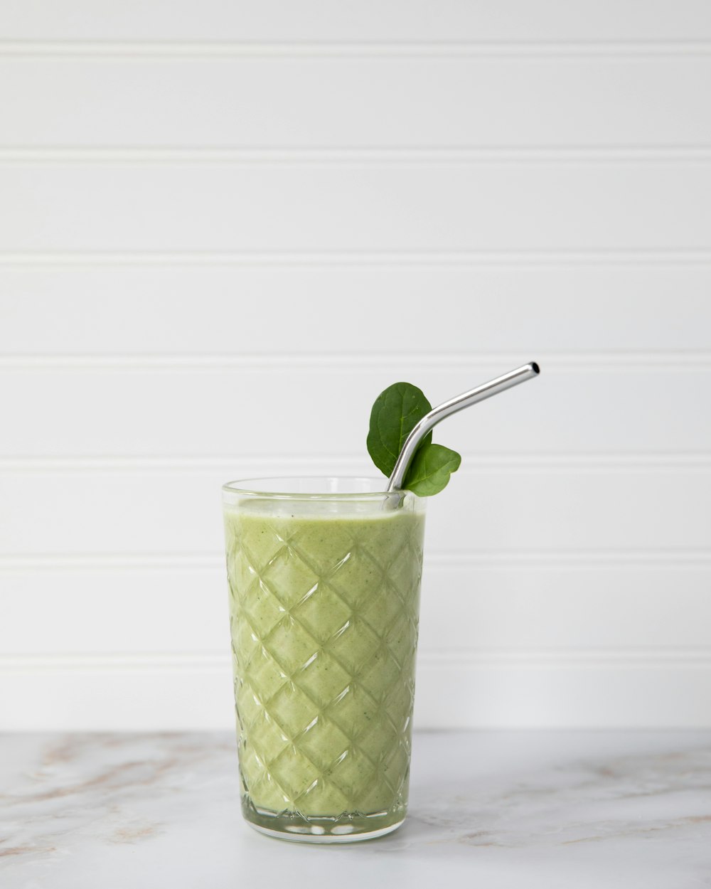 green and white drink with straw in clear drinking glass