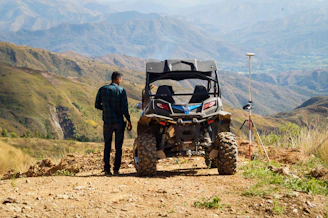 man in black jacket standing beside red and black atv during daytime