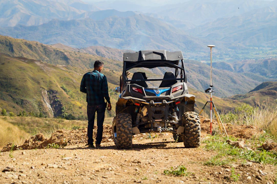 man in black jacket standing beside red and black atv during daytime