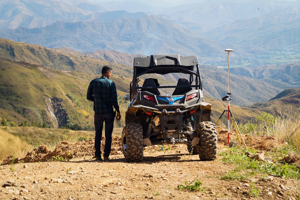 man in black jacket standing beside red and black atv during daytime