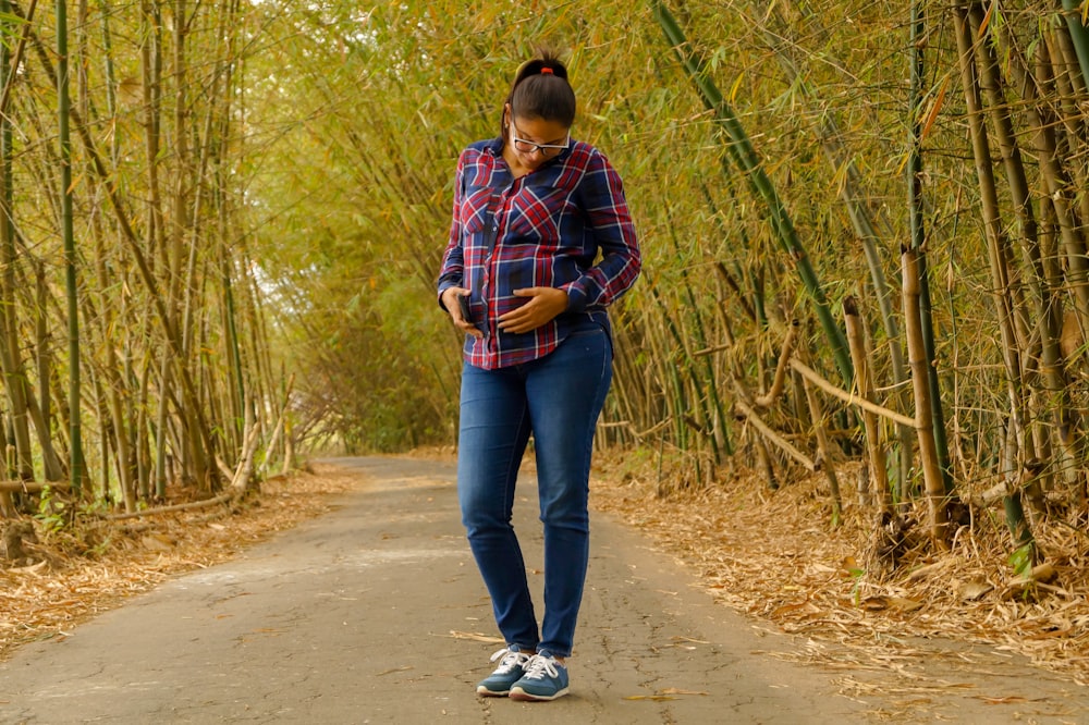 man in red and blue plaid dress shirt and blue denim jeans standing on road during