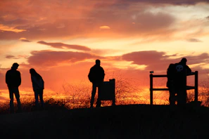 A vibrant sunset with silhouettes of people observing the sky during an astrological event
