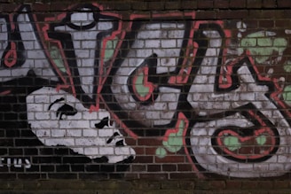 Graffiti artwork on a brick wall depicting elaborate and colorful letters with a stylized black and white face integrated into the design.