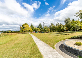Walking with Jesus along green grass field with trees under blue sky and white clouds during daytime