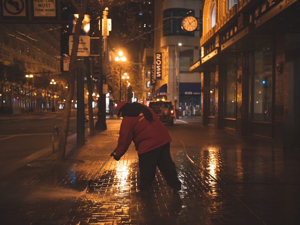 person in red hoodie walking on sidewalk during night time