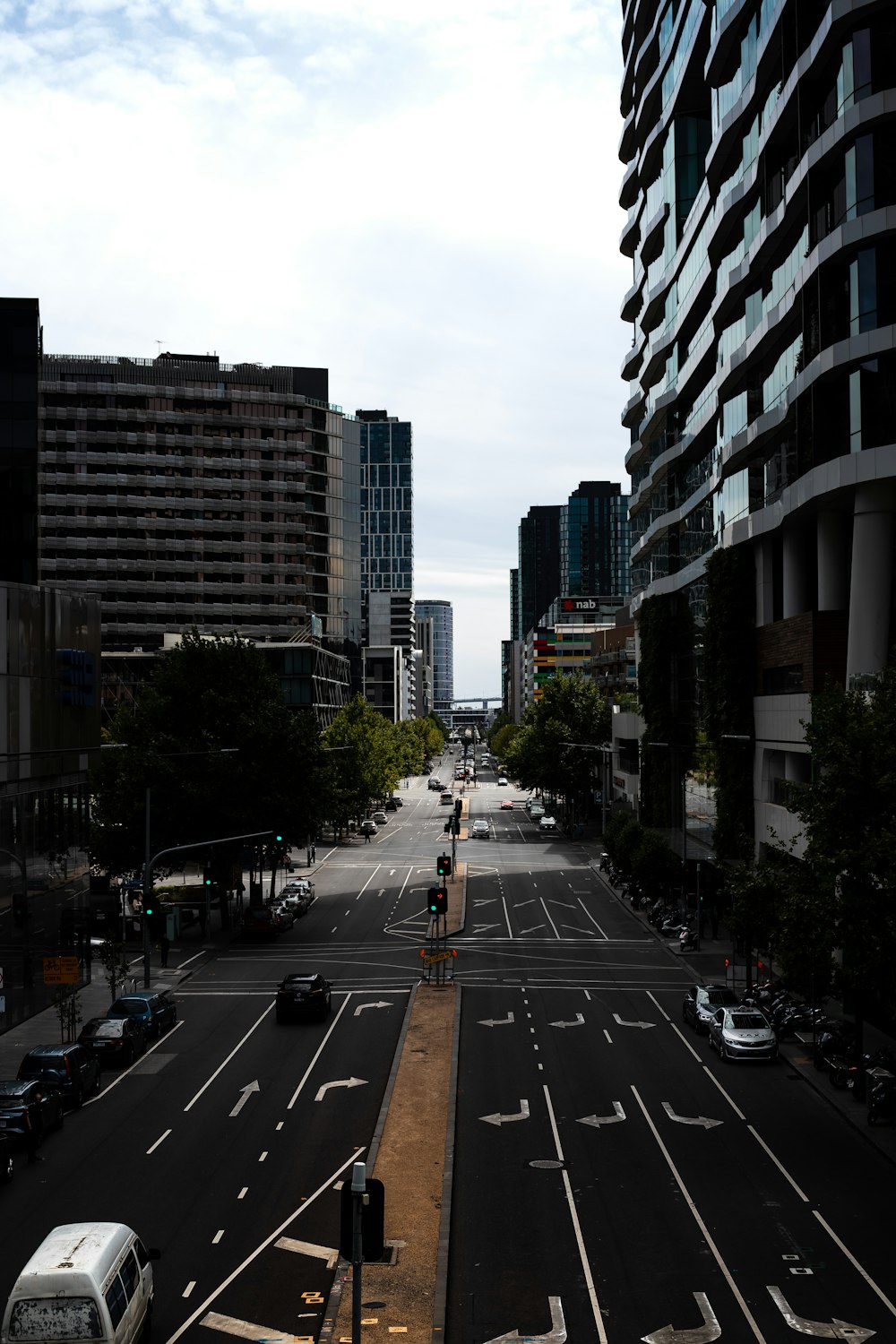 cars on road between high rise buildings during daytime