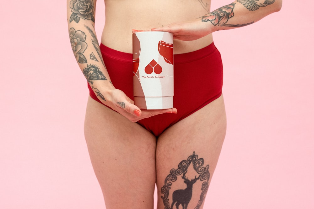 woman in red and white bikini holding white and red ceramic mug