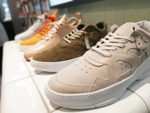 Overhead shot of various sneaker styles laid out on a minimalist green and white backdrop