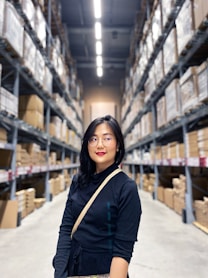 woman in black long sleeve shirt standing near brown wooden shelf