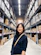 woman in black long sleeve shirt standing near brown wooden shelf