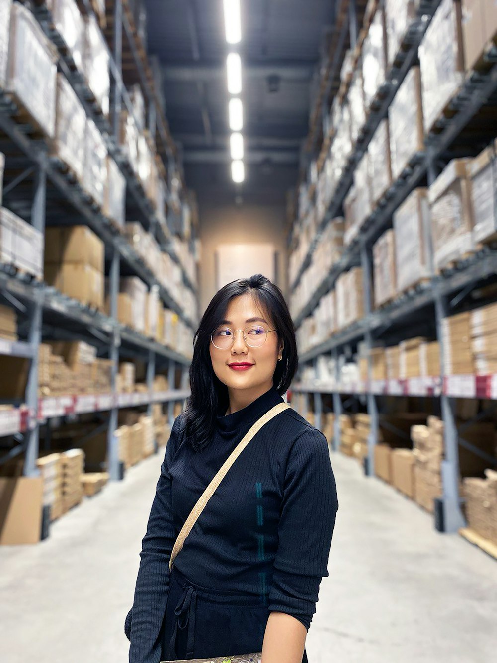 woman in black long sleeve shirt standing near brown wooden shelf