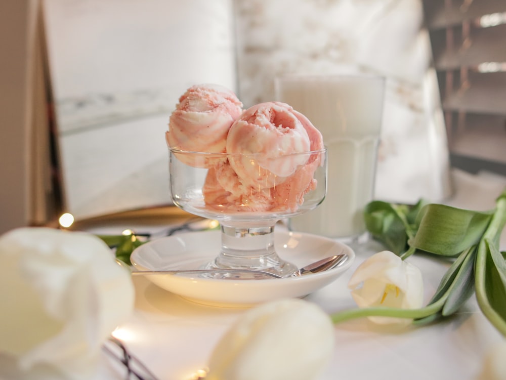 a glass bowl filled with ice cream next to a candle