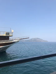 A serene image of a comfortable boat anchored near a rocky Adriatic coastline with calm water and warm sunlight.