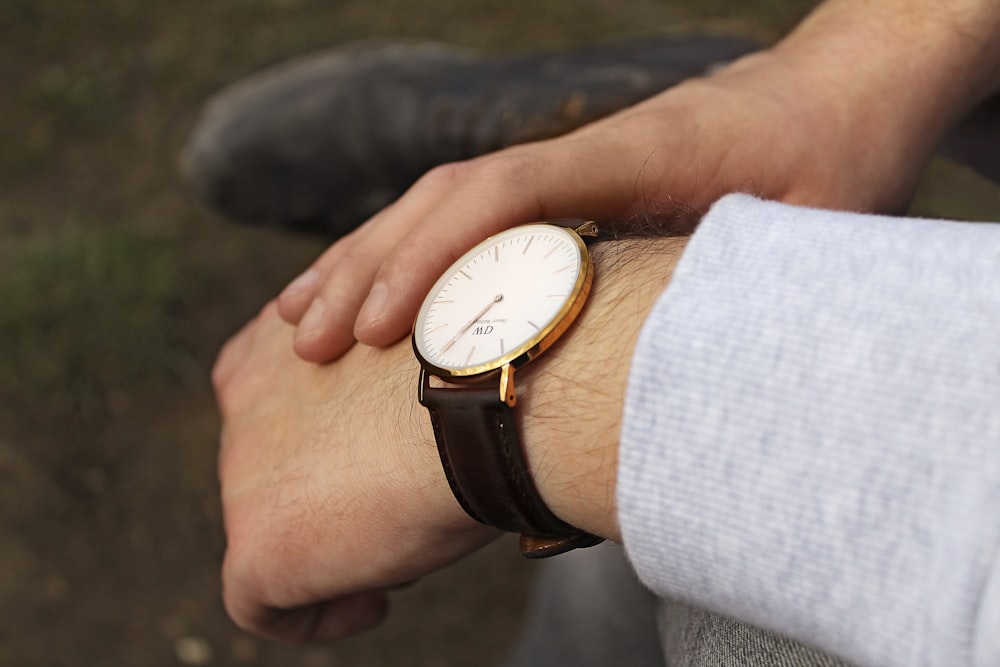 person wearing black leather strap silver round analog watch