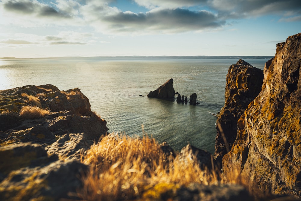 brown rock formation on sea under white clouds during daytime