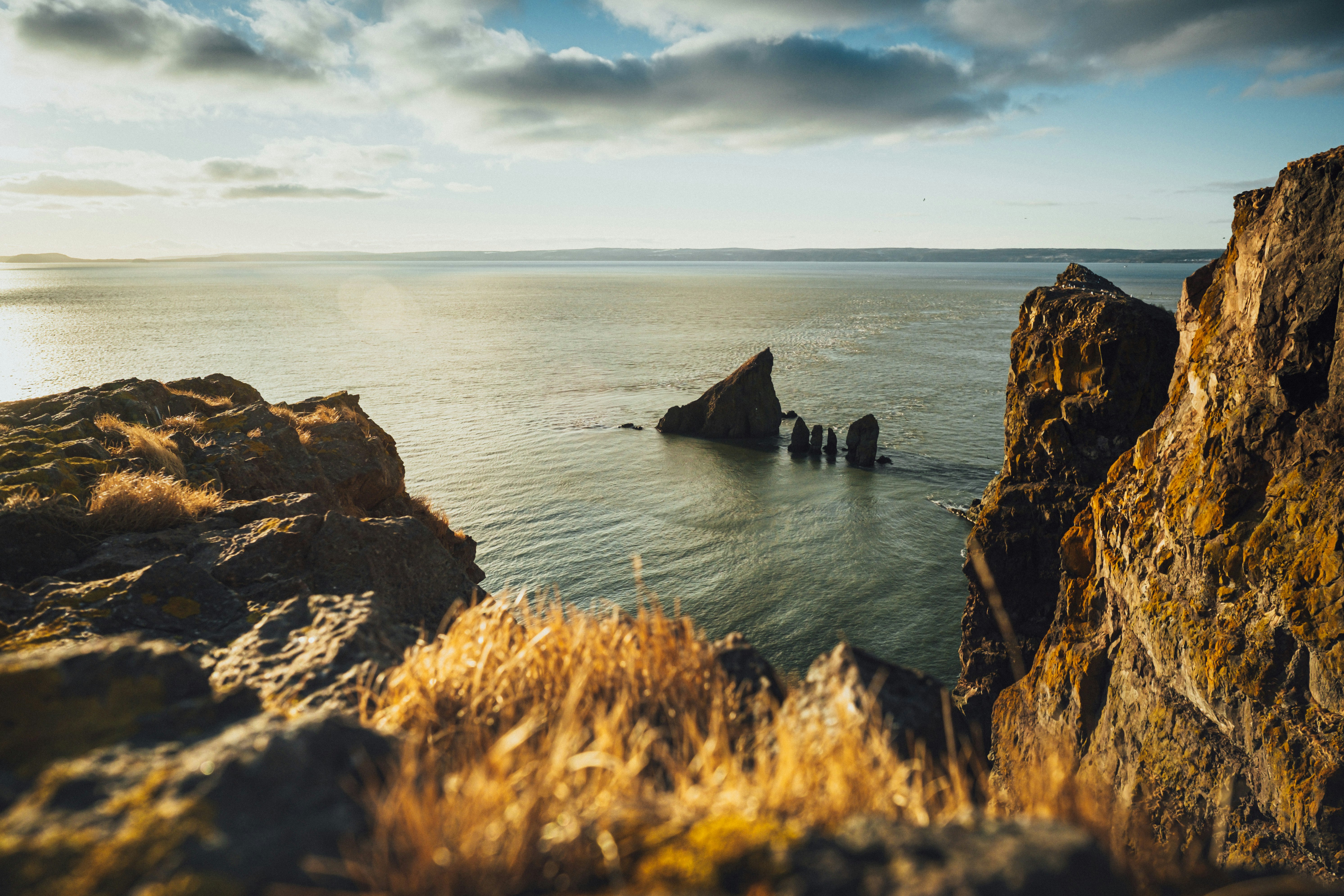 brown rock formation on sea under white clouds during daytime