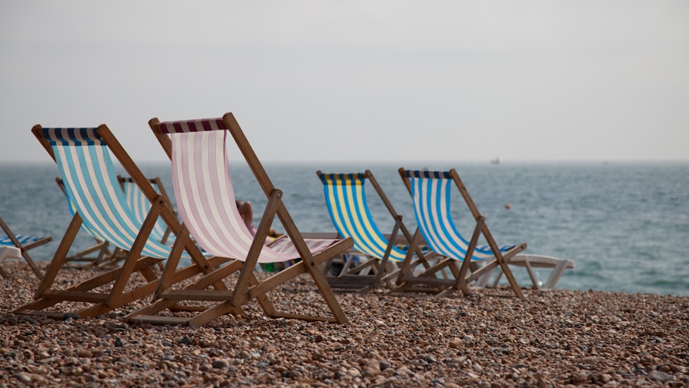 blue and white striped folding chairs on beach during daytime