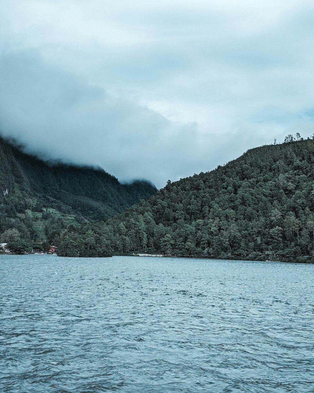 people riding boat on sea near green mountain under white clouds during daytime