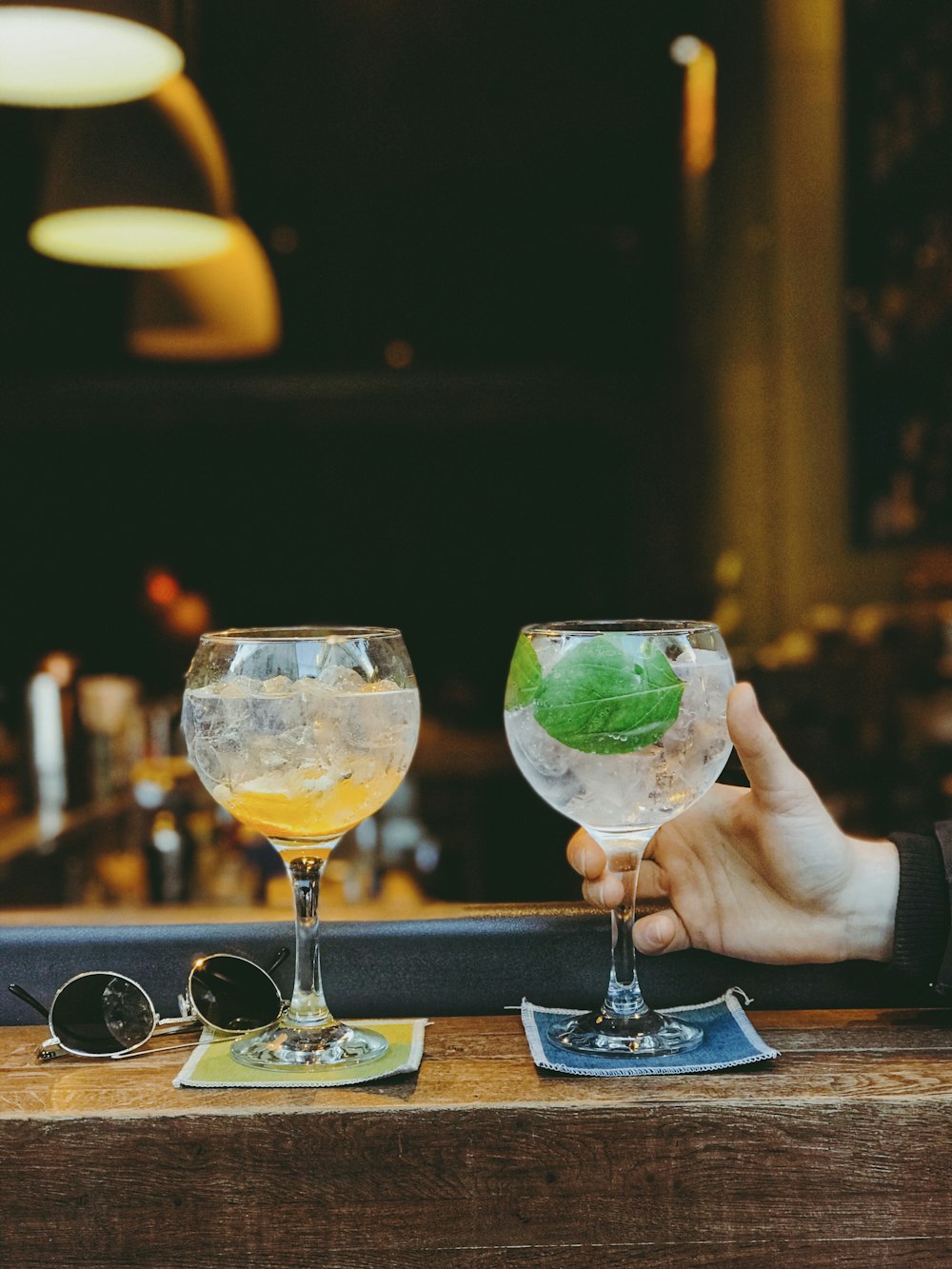 person holding clear wine glass with yellow liquid