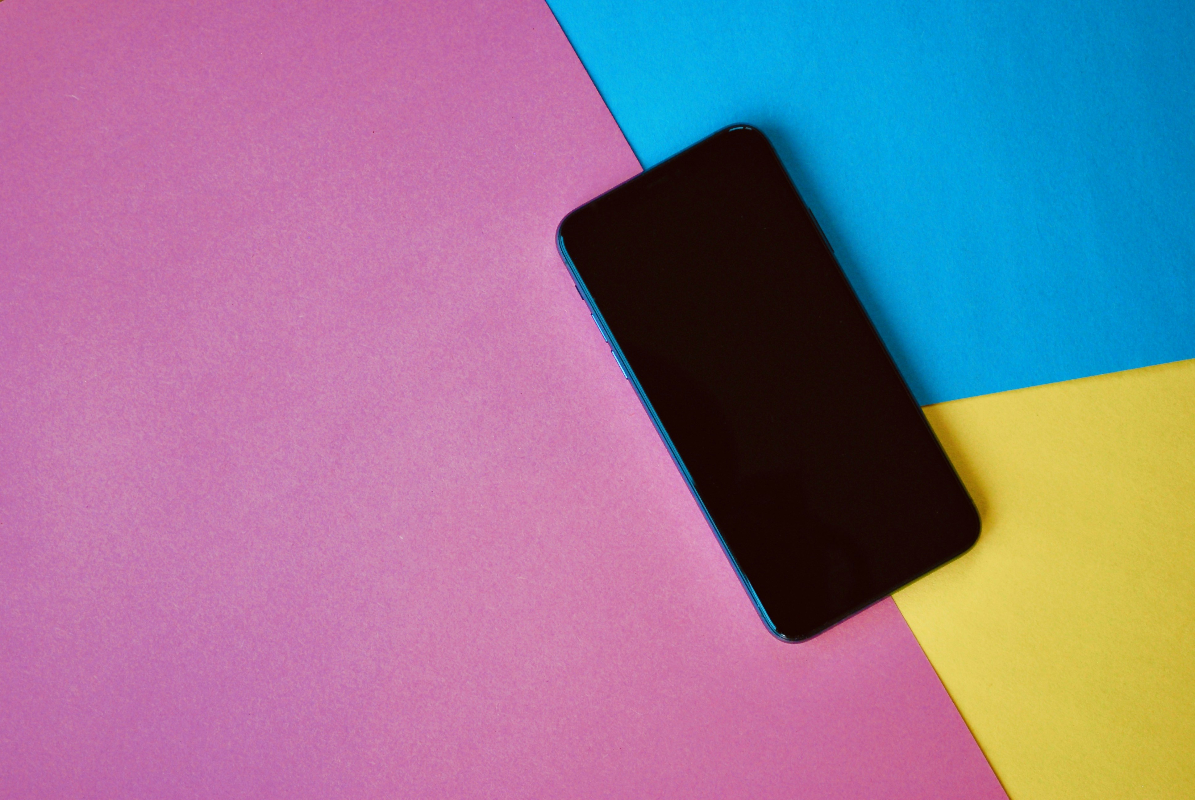 black smartphone on pink and blue textile