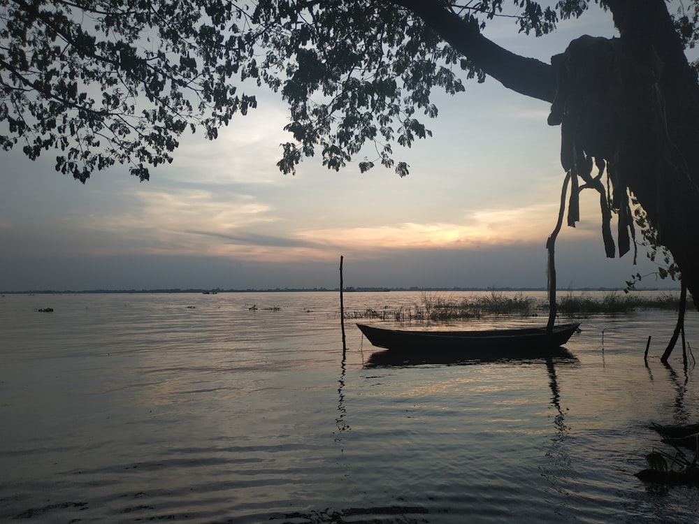 silhouette of woman on boat on water during sunset