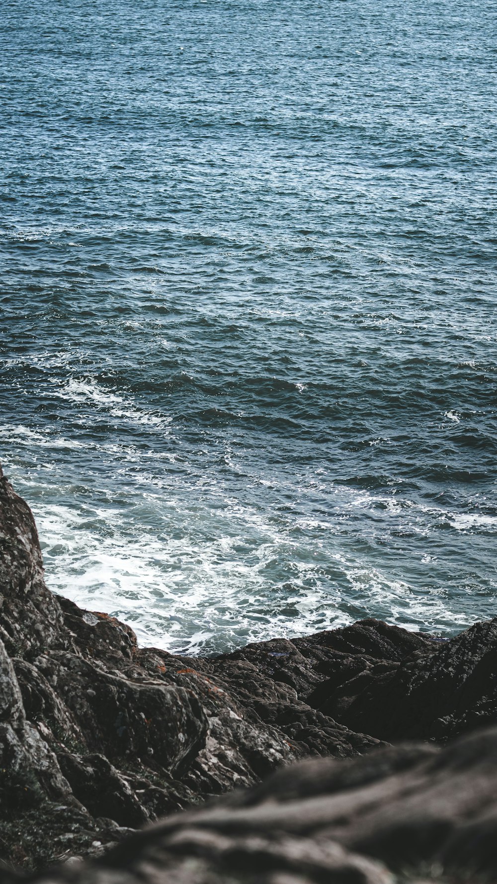 blue sea waves crashing on brown rocky shore during daytime