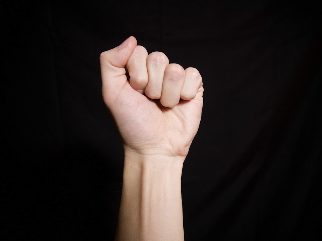 persons left hand on black textile, Fist!