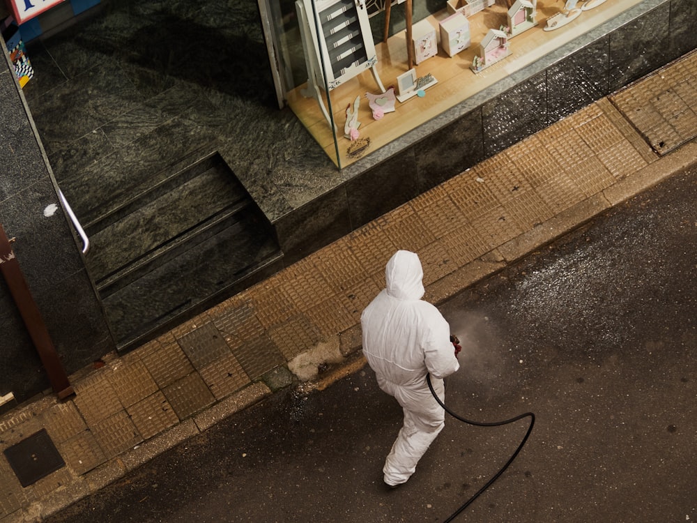 homem em thobe branco andando na calçada durante o dia