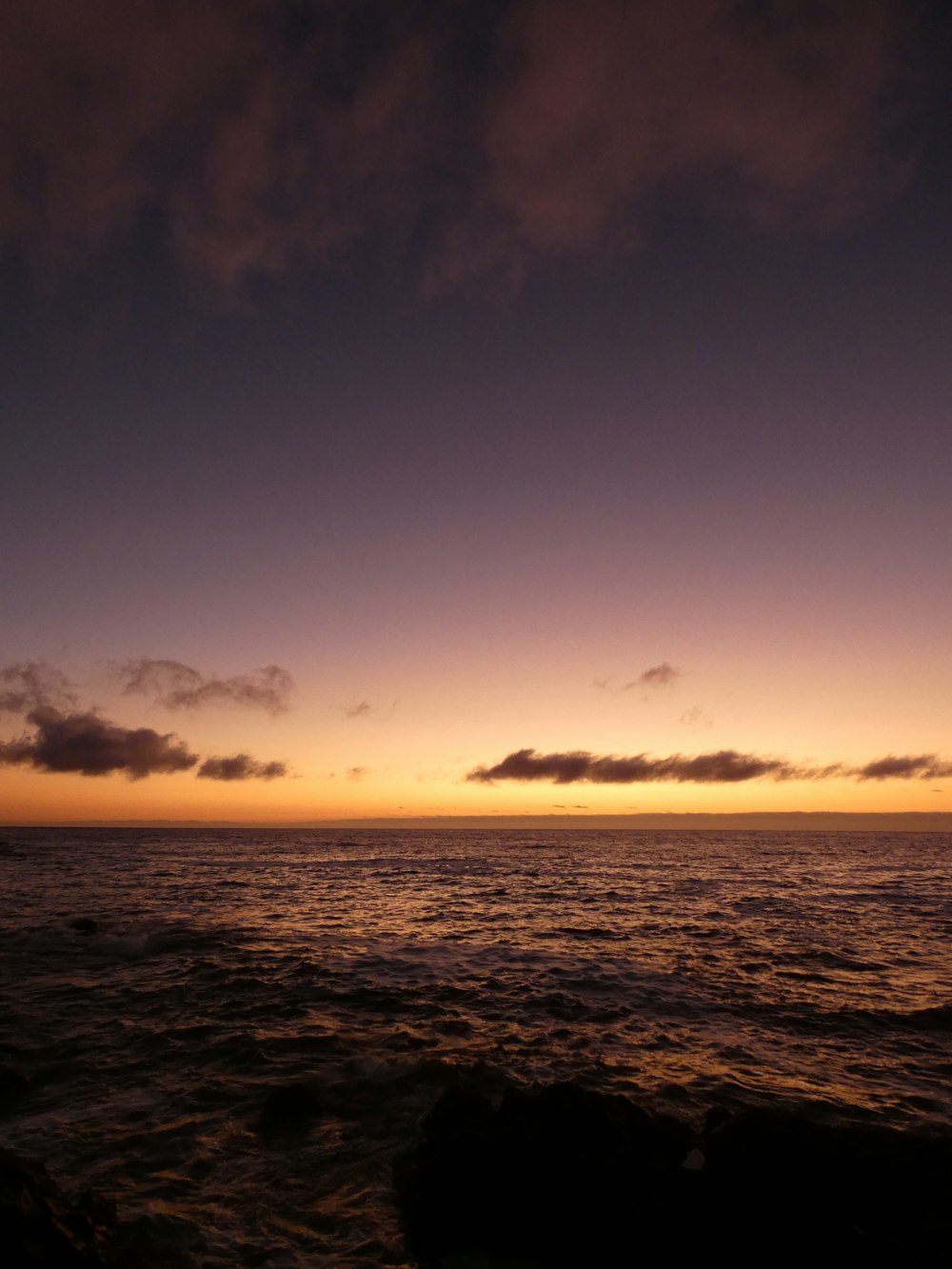 the sun is setting over the ocean on a cloudy day