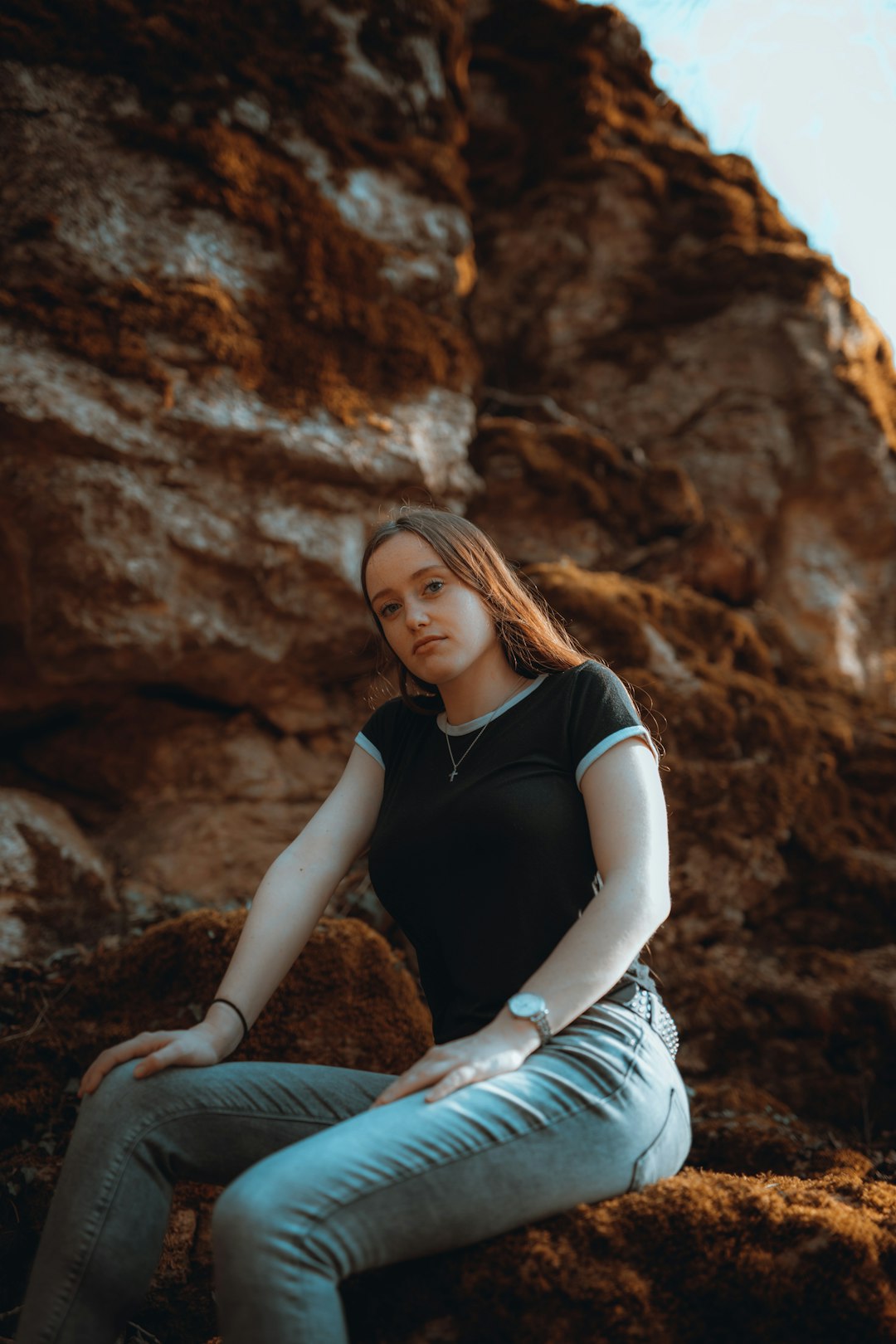 woman in black shirt and white skirt sitting on rock