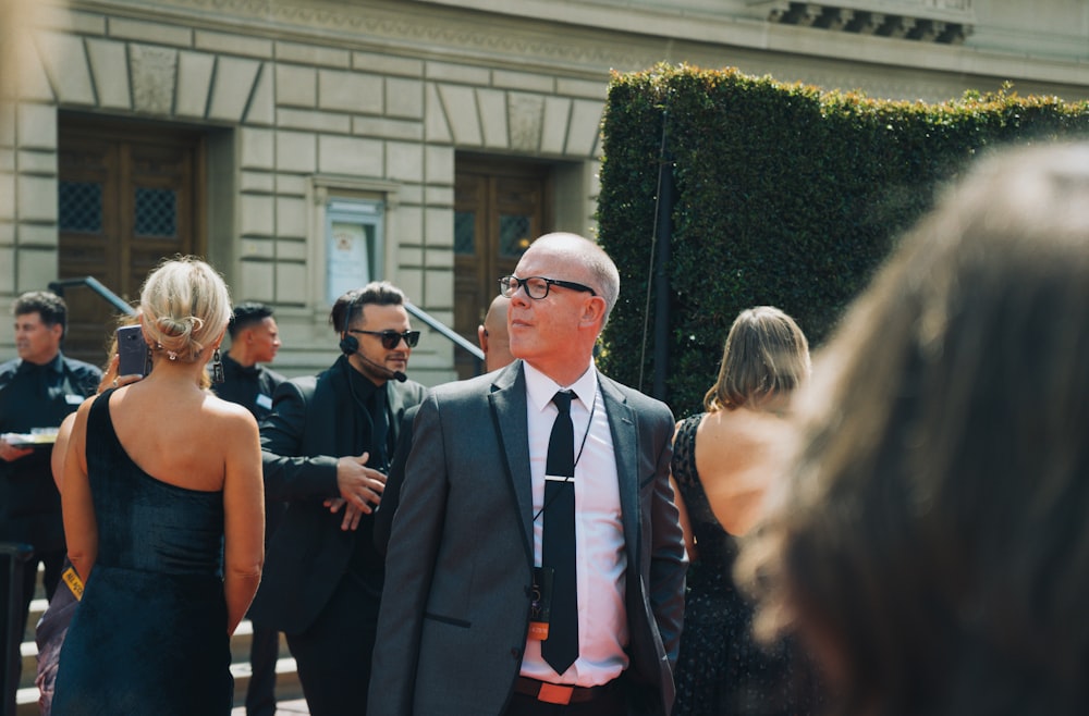 man in black suit standing beside woman in black sleeveless dress