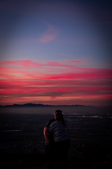 A breathtaking sunset over the Rocky Mountains with a couple sharing a quiet moment during their wedding shoot.