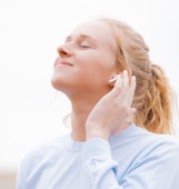 woman in white crew neck shirt covering her face with her hand