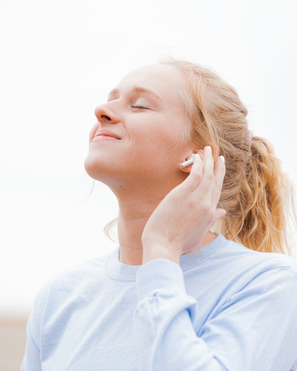 woman in white crew neck shirt covering her face with her hand