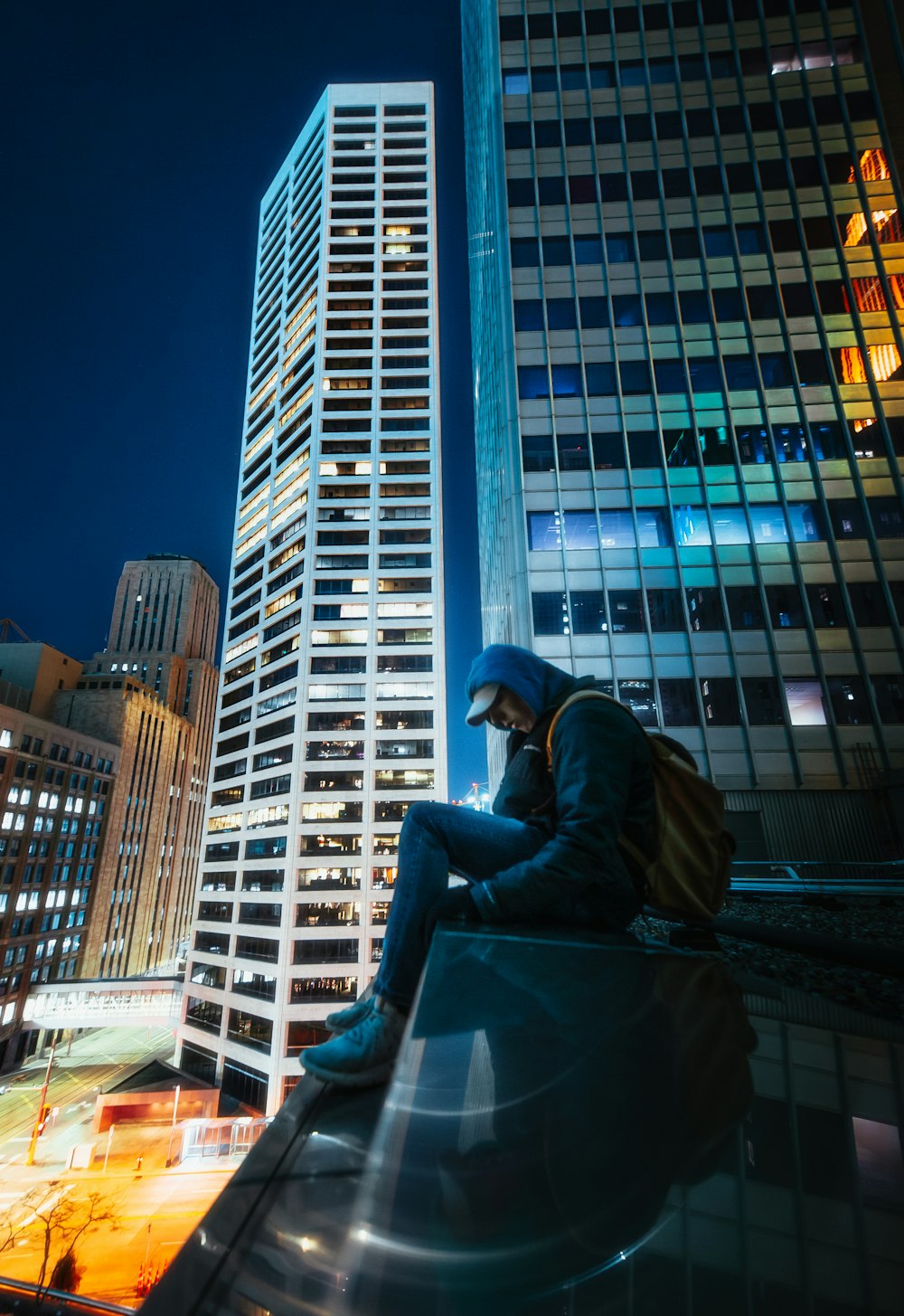 man in black jacket sitting on the edge of a building