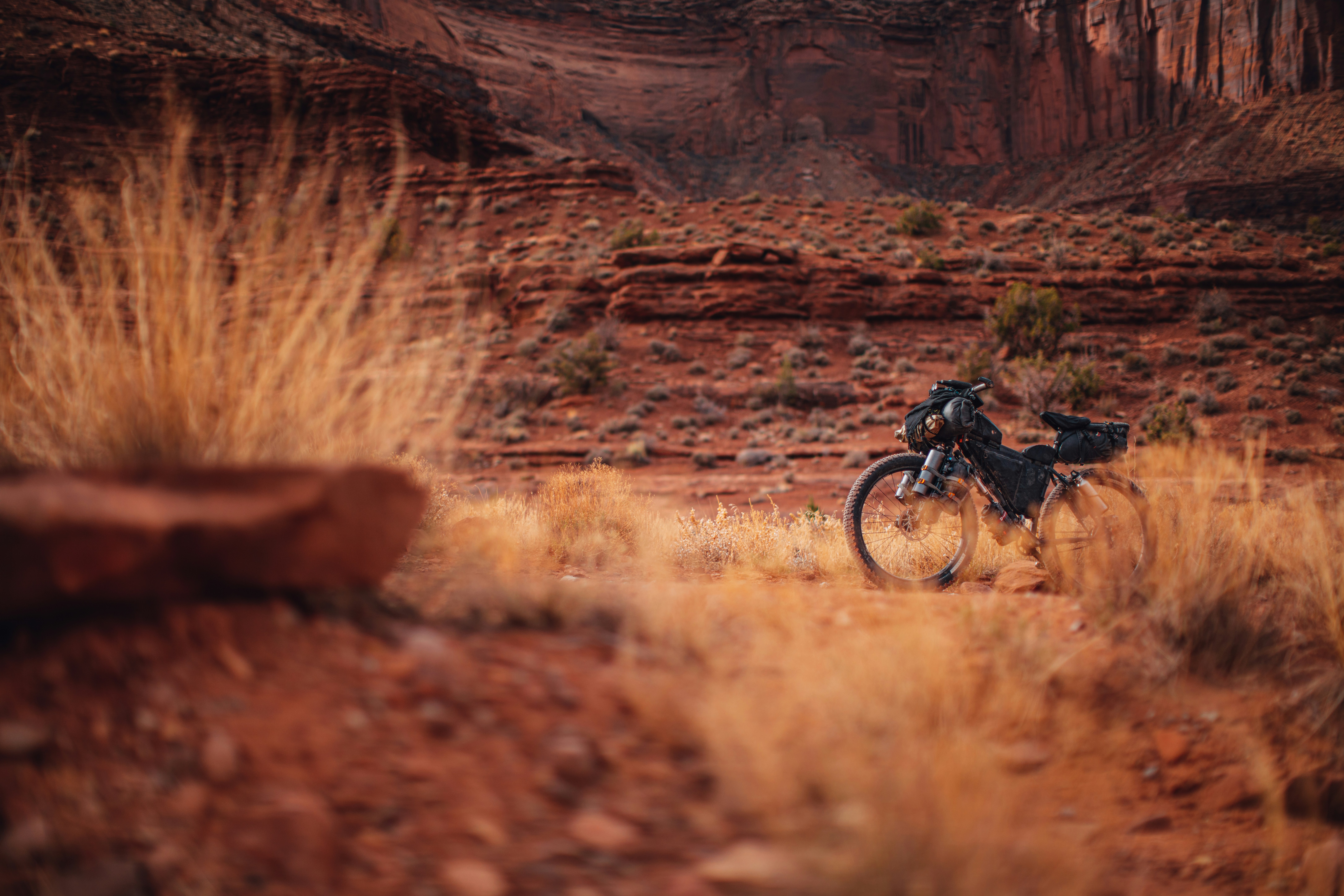 man in black jacket riding bicycle on brown field during daytime