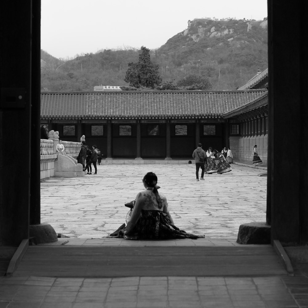 grayscale photo of people sitting on wooden bench