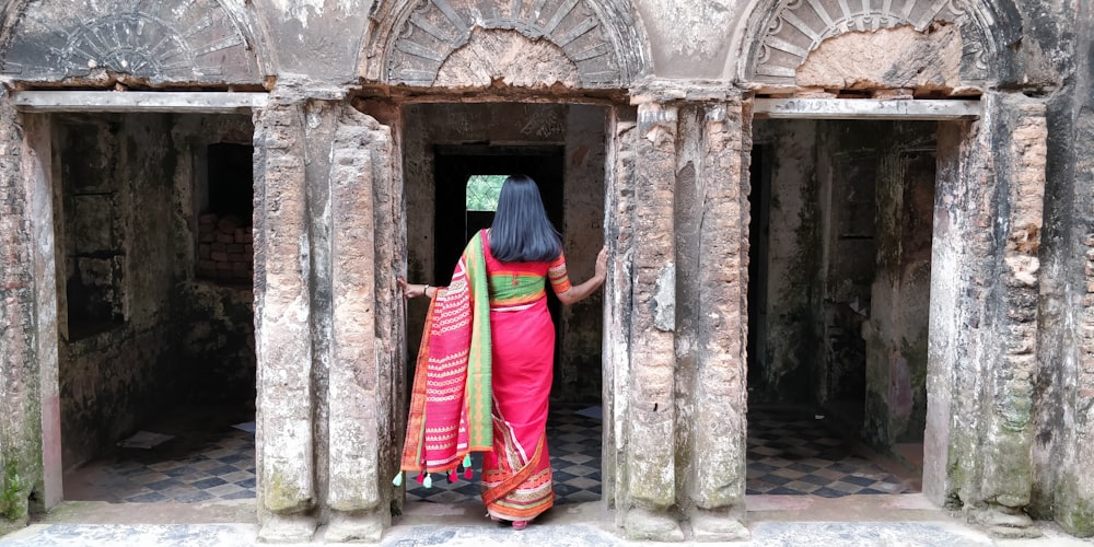 woman in blue and red sari standing in front of brown wooden door