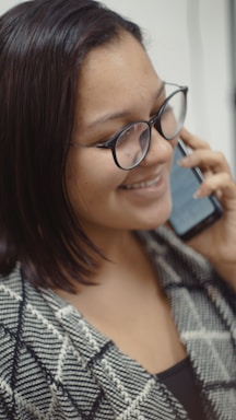 A person happily chatting on their phone with sneakers visible in the background.