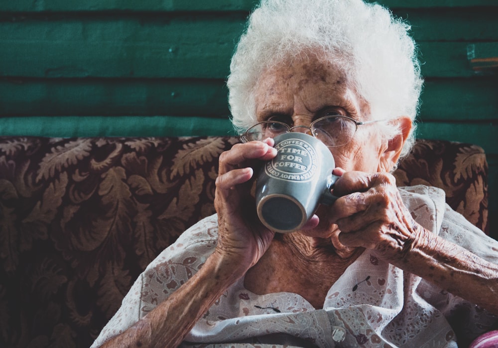 man drinking from white ceramic mug